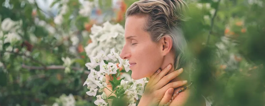 Eine Frau mit geschlossenen Augen zwischen weißen Blüten im Garten von Kamalaya auf Koh Samui