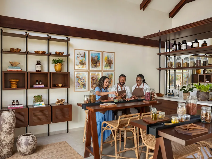 Gäste mischen Kräuter und Pflanzenstoffe an einem Werkstatttisch zwischen Gläsern und Regalen bei Six Senses